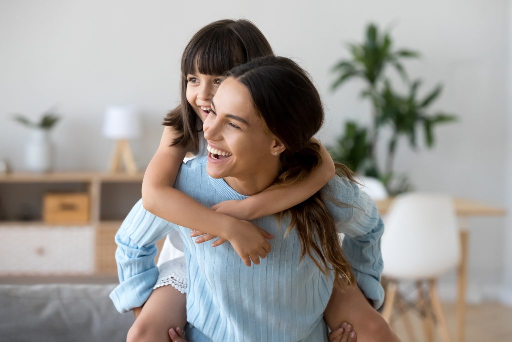 mom who knows how to make mom life better, giving her daughter a piggy back ride and laughing together