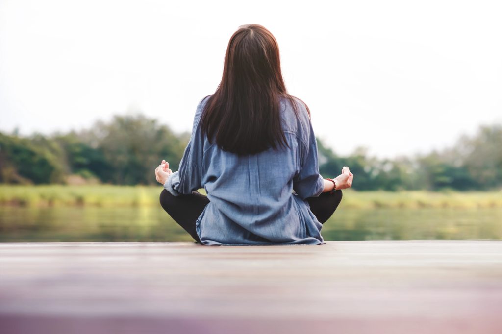 woman practicing self-care ideas for moms - meditating outside